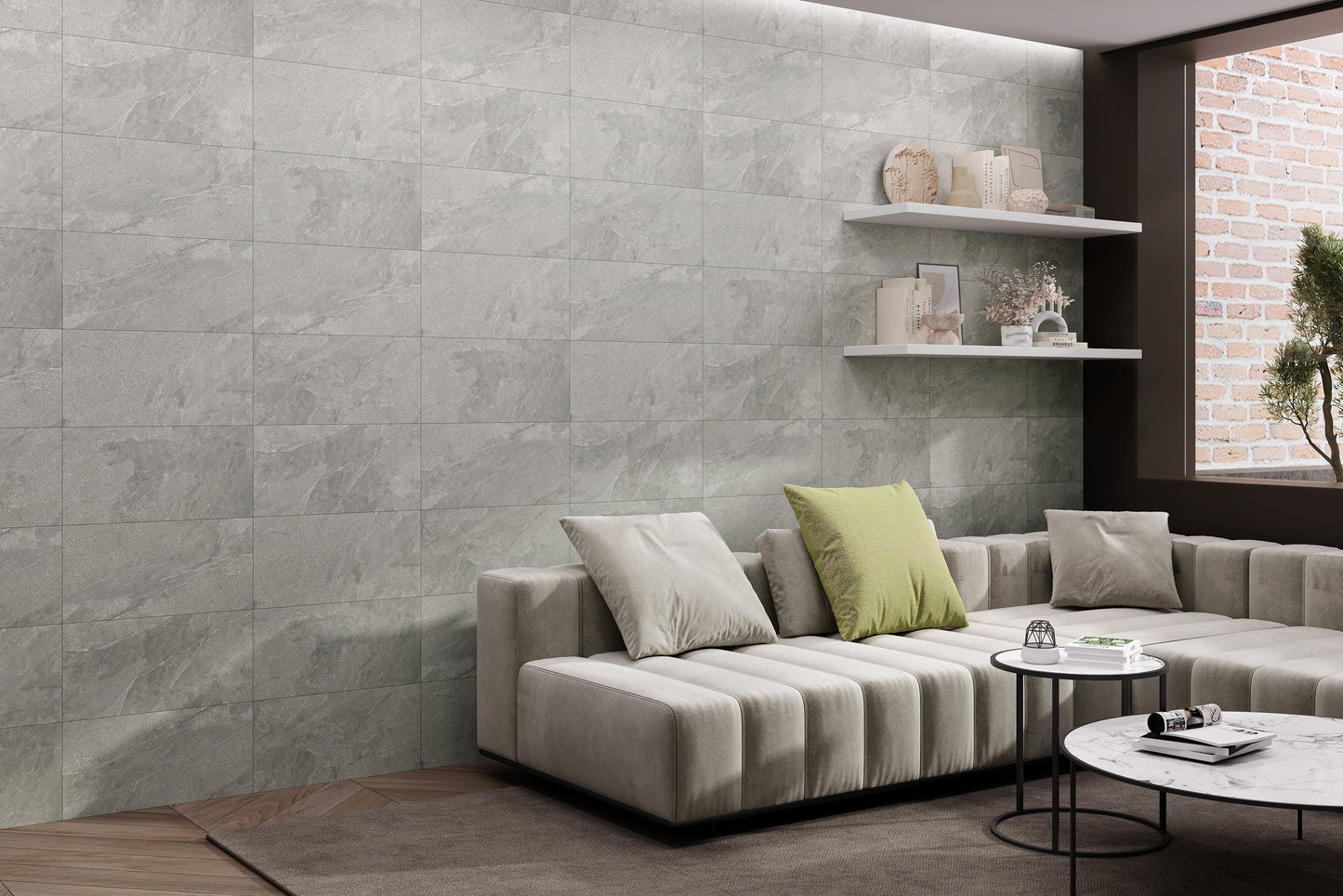 Modern living room with a gray sofa, coffee table, and decorative items against a stone wall. 