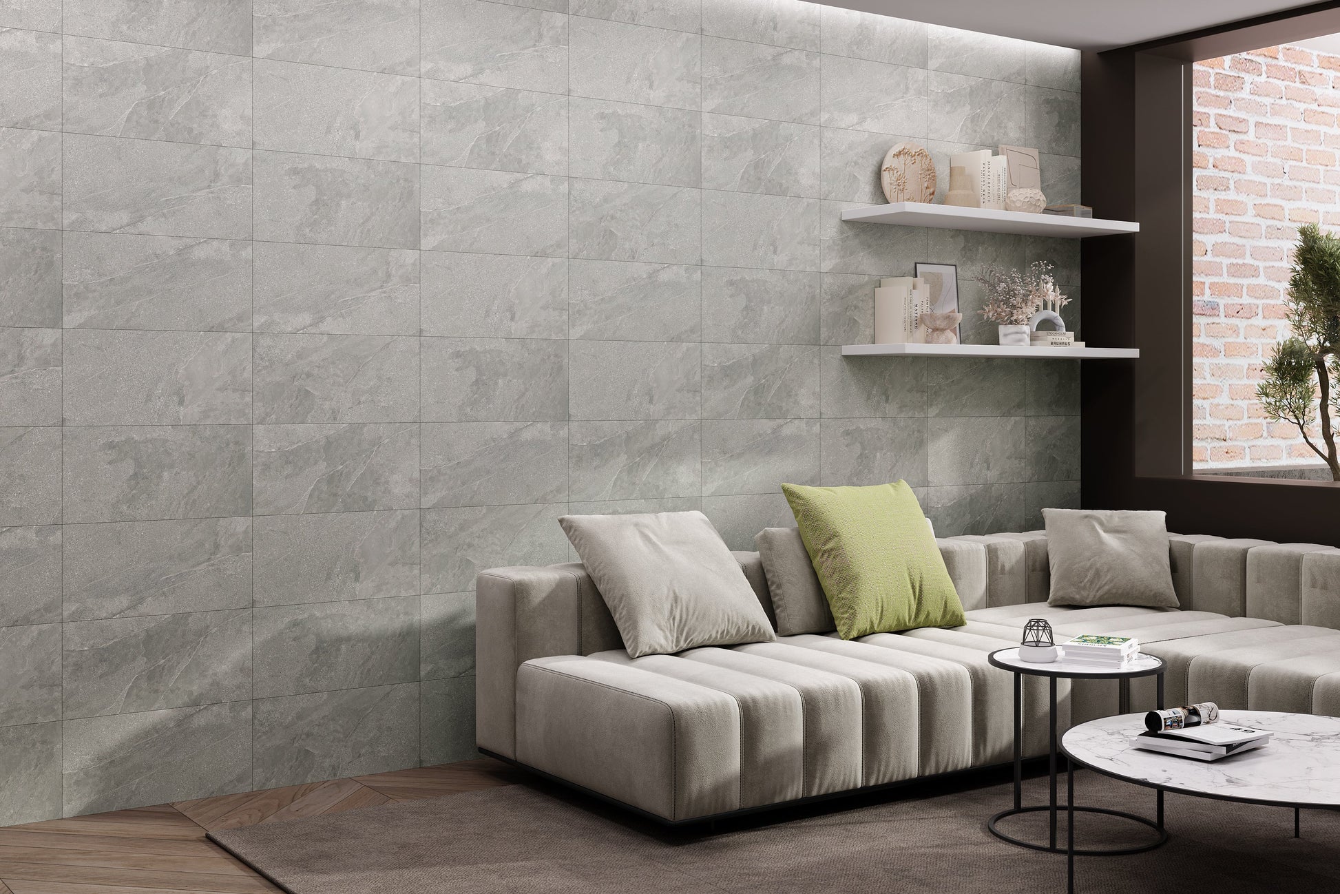 Modern living room with a gray sofa, coffee table, and decorative items against a stone wall. 