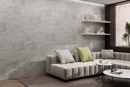 Modern living room with a gray sofa, coffee table, and decorative items against a stone wall. 